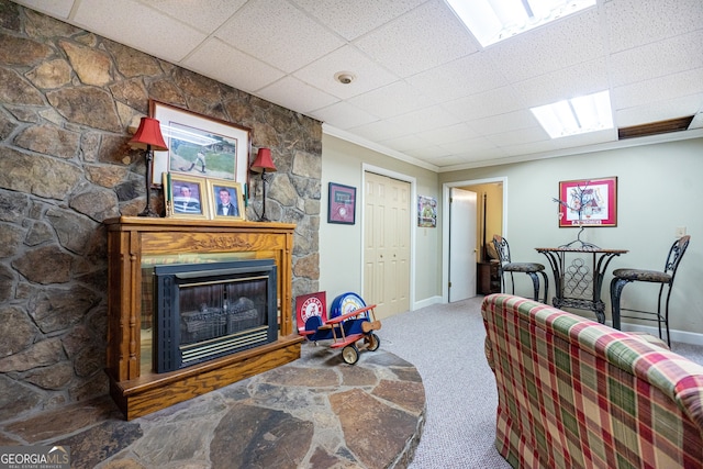 living room featuring carpet, a fireplace, a paneled ceiling, and crown molding