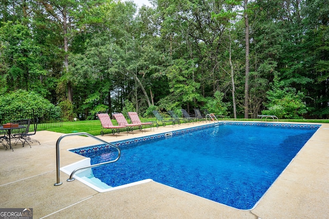 view of pool featuring a patio and a yard