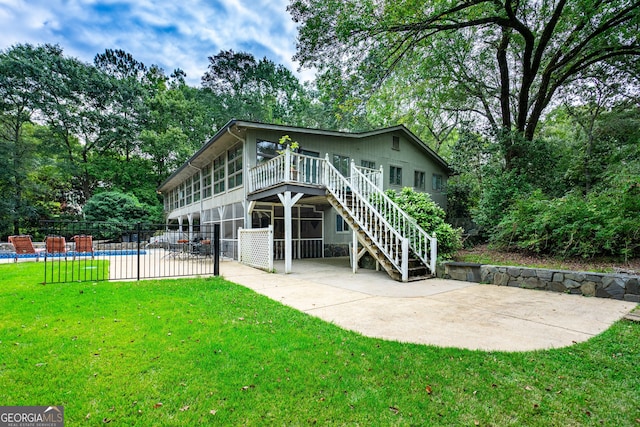 back of house featuring a lawn, a patio area, and a pool side deck