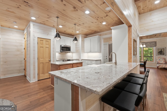 kitchen featuring white cabinets, wood walls, a center island, and hardwood / wood-style floors