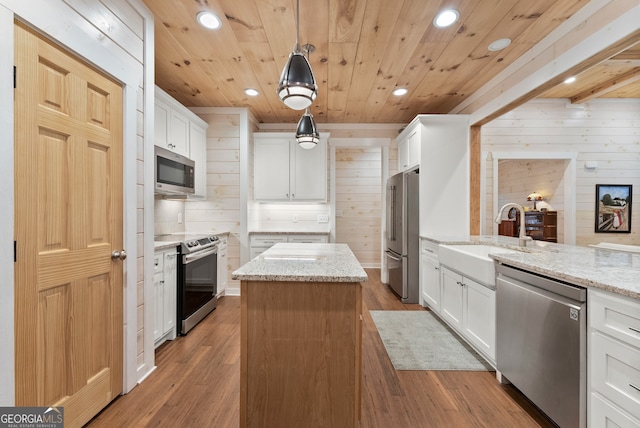 kitchen featuring stainless steel appliances, white cabinets, and decorative light fixtures