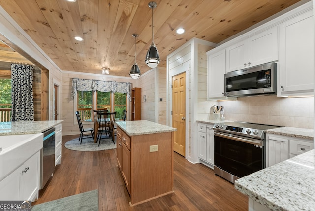 kitchen featuring white cabinets, a kitchen island, wood-type flooring, decorative light fixtures, and stainless steel appliances