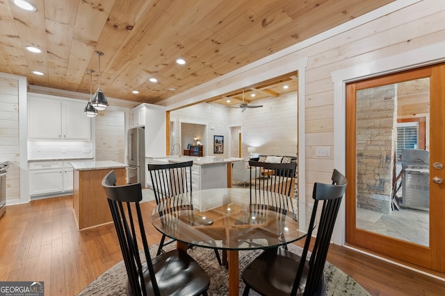 dining room with wood ceiling, light hardwood / wood-style floors, and wood walls