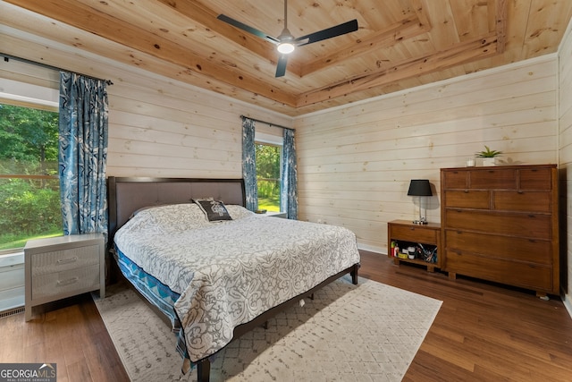 bedroom featuring wood ceiling, a raised ceiling, wood-type flooring, ceiling fan, and wooden walls