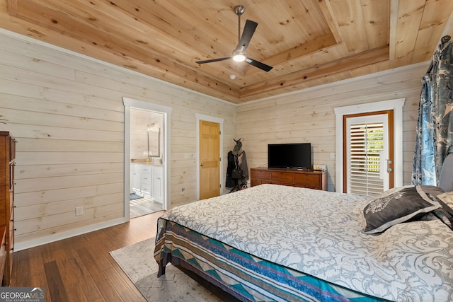 bedroom featuring ceiling fan, hardwood / wood-style flooring, wooden walls, and ensuite bathroom