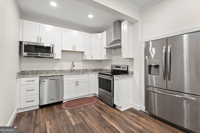 kitchen featuring dark hardwood / wood-style floors, white cabinets, wall chimney range hood, stainless steel appliances, and crown molding