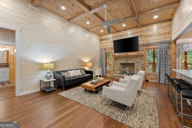 living room with beam ceiling, ceiling fan, a fireplace, and hardwood / wood-style floors