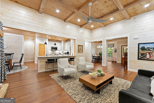 living room featuring ceiling fan, beamed ceiling, wooden walls, dark hardwood / wood-style floors, and wooden ceiling