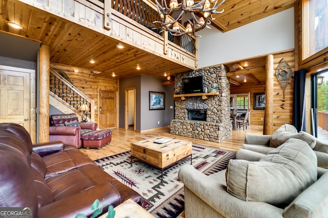 living room featuring a chandelier, hardwood / wood-style flooring, a stone fireplace, a high ceiling, and wooden ceiling