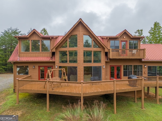 back of house featuring a balcony, a deck, and a lawn