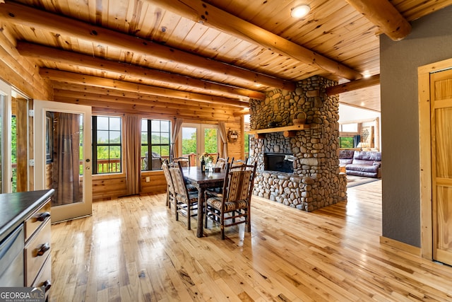 dining room featuring beamed ceiling, a fireplace, plenty of natural light, and light hardwood / wood-style floors