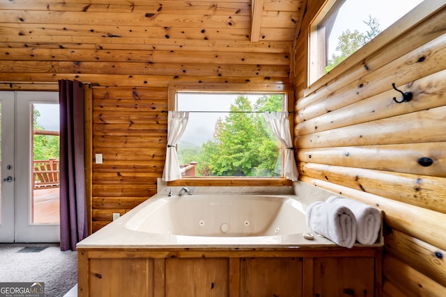 bathroom with a bath, a healthy amount of sunlight, beam ceiling, and rustic walls