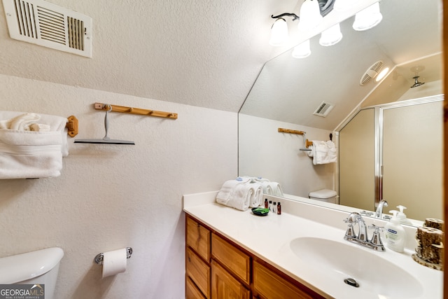 bathroom with vaulted ceiling, a shower with shower door, vanity, and toilet