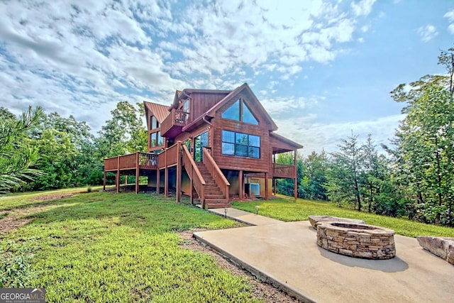 rear view of house featuring a deck, a yard, and a fire pit