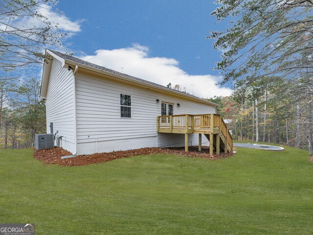 rear view of house featuring central air condition unit, a yard, and a deck