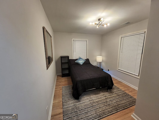 bedroom featuring baseboards, visible vents, and wood finished floors