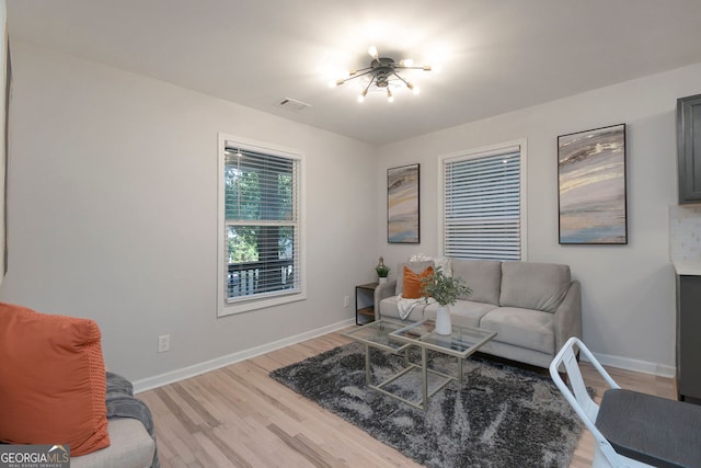 living room featuring light wood-style flooring, visible vents, and baseboards