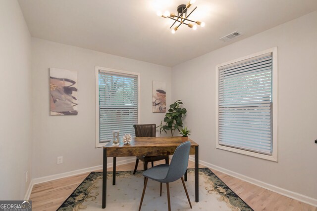 home office featuring light wood-type flooring, baseboards, visible vents, and a notable chandelier