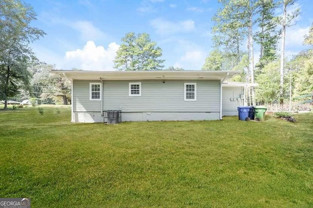 rear view of property featuring a lawn and central AC