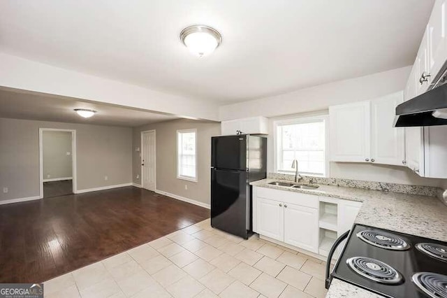 kitchen featuring a wealth of natural light, light hardwood / wood-style floors, black refrigerator, and sink