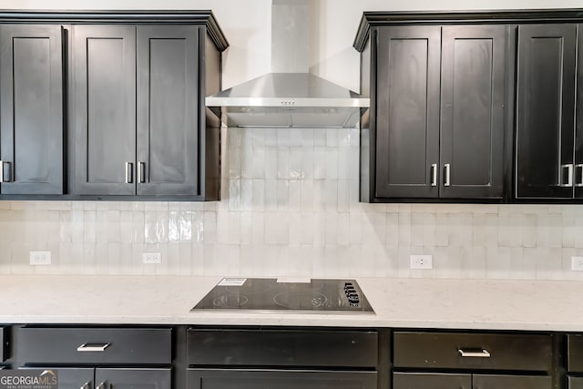 kitchen featuring black electric cooktop, decorative backsplash, wall chimney exhaust hood, and light stone countertops