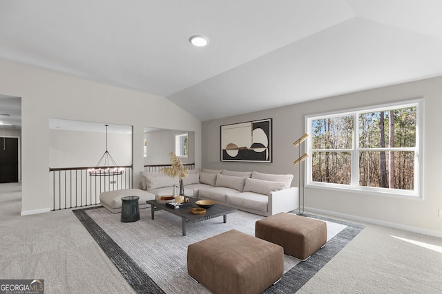 carpeted living room featuring lofted ceiling and an inviting chandelier