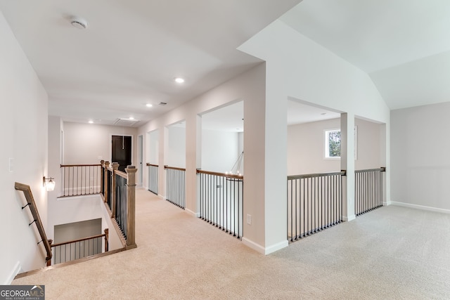 hallway with light carpet and vaulted ceiling