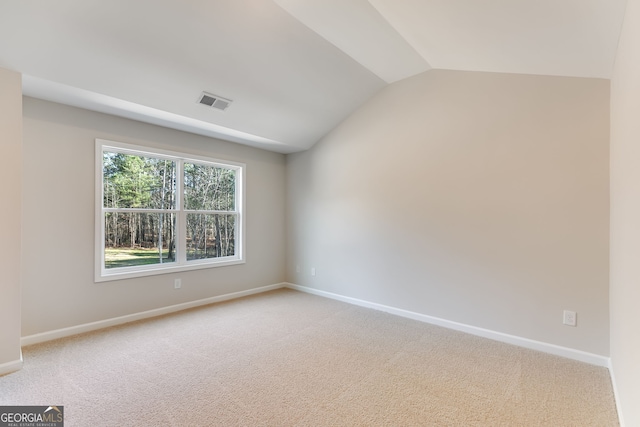 carpeted spare room featuring lofted ceiling