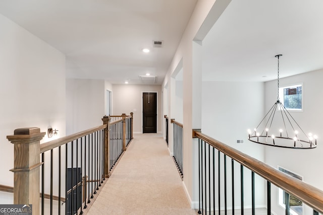 hallway with light colored carpet and an inviting chandelier