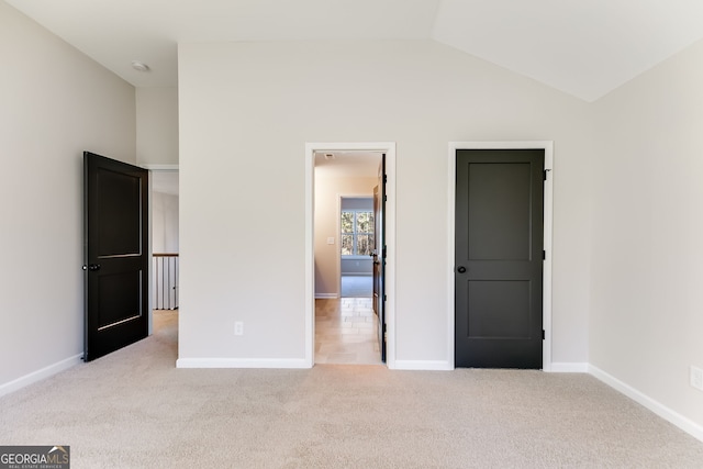 unfurnished bedroom with light colored carpet and vaulted ceiling