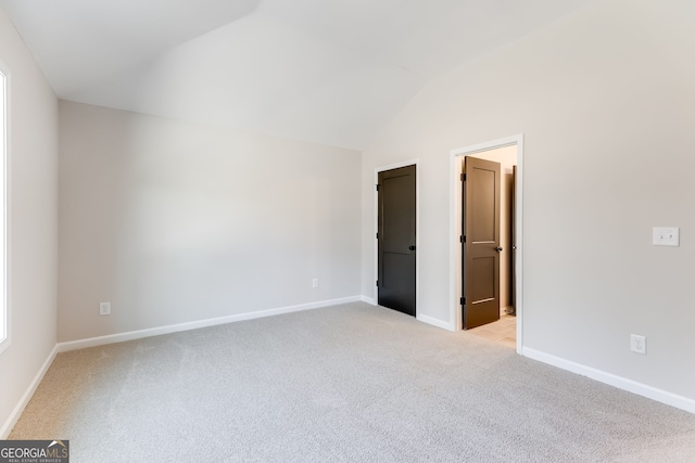 unfurnished bedroom featuring lofted ceiling and light carpet