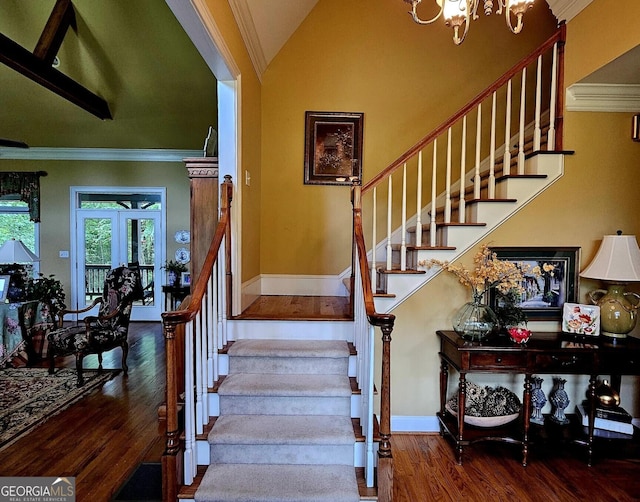 staircase with an inviting chandelier, lofted ceiling, crown molding, and hardwood / wood-style floors