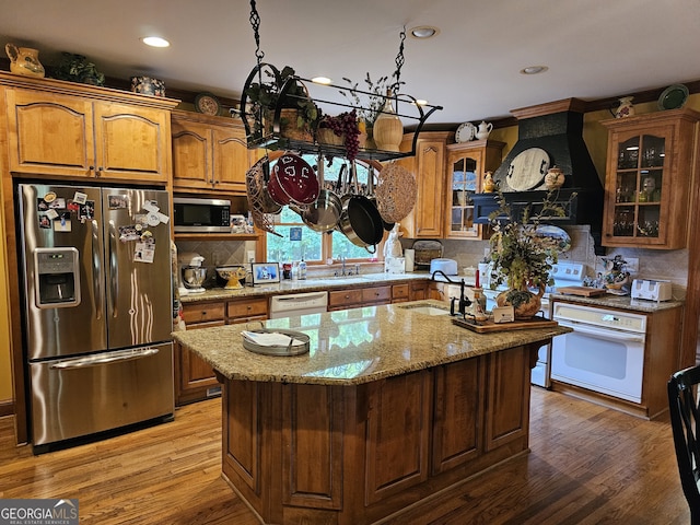 kitchen with decorative backsplash, stainless steel appliances, light hardwood / wood-style flooring, a center island with sink, and a chandelier