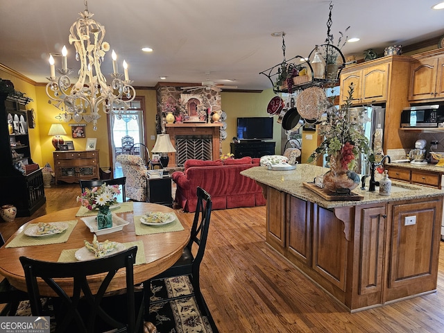 dining room with a stone fireplace, hardwood / wood-style flooring, and crown molding