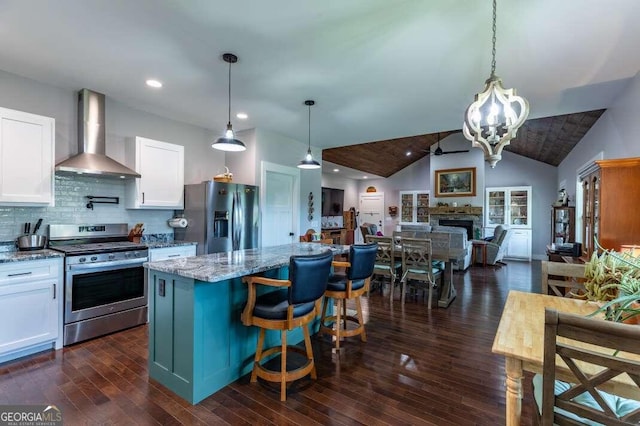 kitchen featuring hanging light fixtures, a kitchen island, appliances with stainless steel finishes, a fireplace, and vaulted ceiling