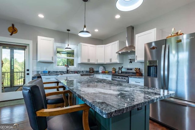 kitchen with white cabinets, lofted ceiling, wall chimney range hood, stainless steel appliances, and light stone countertops