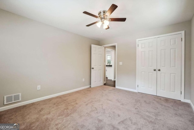 unfurnished bedroom featuring carpet flooring, sink, ceiling fan, and a closet