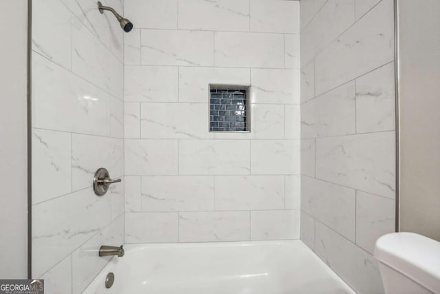 bathroom with tiled shower / bath and toilet