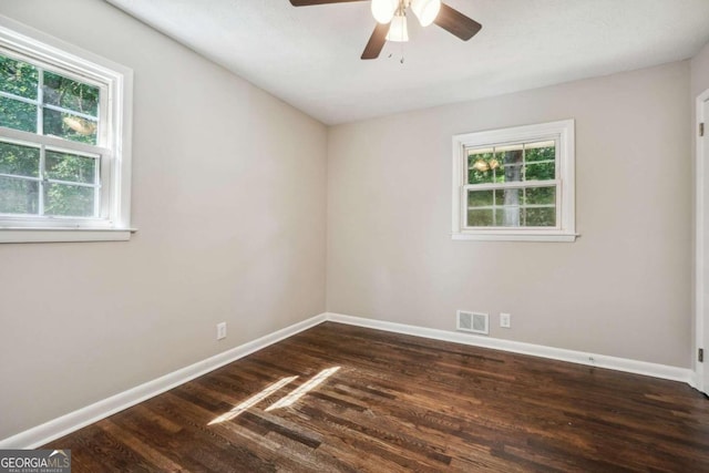 spare room with ceiling fan, plenty of natural light, and dark wood-type flooring