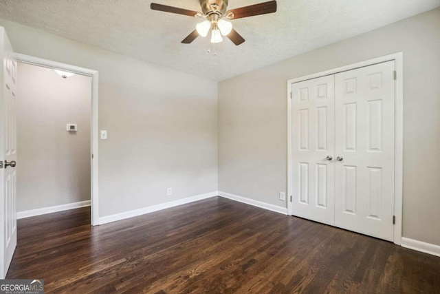 unfurnished bedroom featuring ceiling fan, a textured ceiling, a closet, and dark wood-type flooring