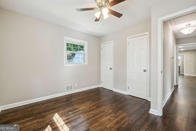 unfurnished bedroom with ceiling fan and dark wood-type flooring