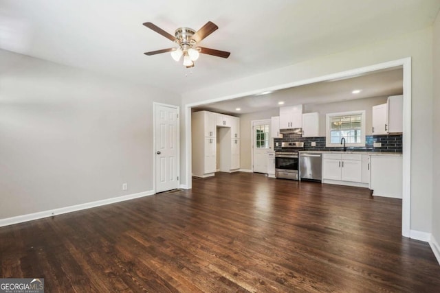 unfurnished living room featuring dark hardwood / wood-style floors, ceiling fan, and sink