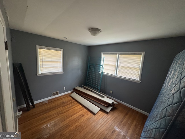 unfurnished bedroom with hardwood / wood-style flooring and multiple windows