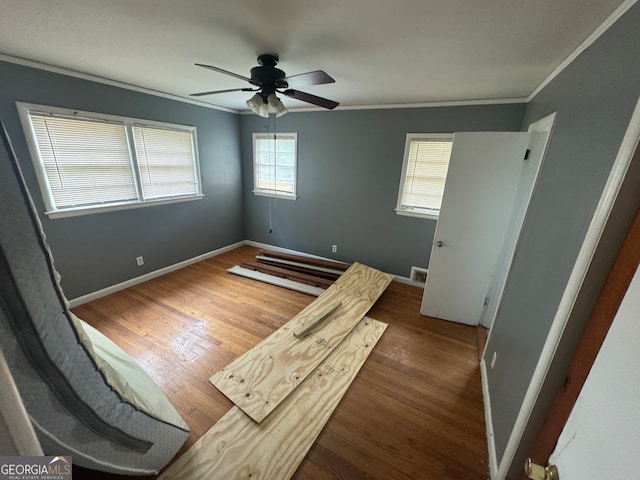 unfurnished bedroom featuring ceiling fan, dark wood-type flooring, and crown molding