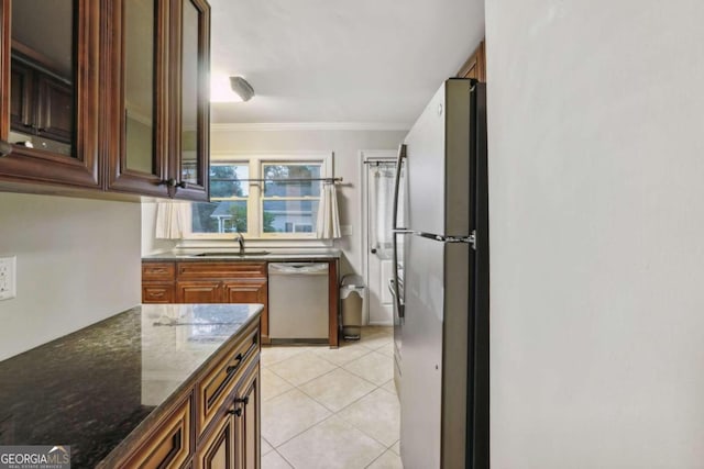 kitchen featuring stainless steel appliances, sink, dark stone counters, crown molding, and light tile patterned floors