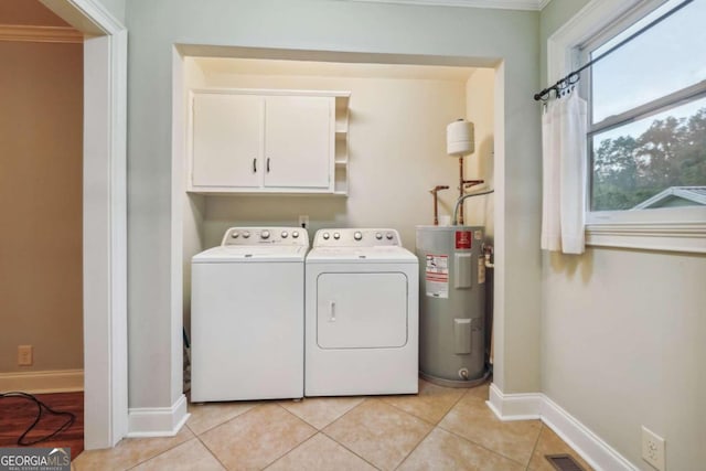 clothes washing area featuring electric water heater, light tile patterned flooring, crown molding, cabinets, and washing machine and dryer