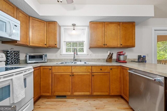 kitchen featuring light hardwood / wood-style floors, a healthy amount of sunlight, white appliances, and sink