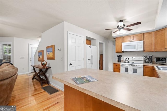 kitchen with kitchen peninsula, white appliances, light hardwood / wood-style floors, and ceiling fan