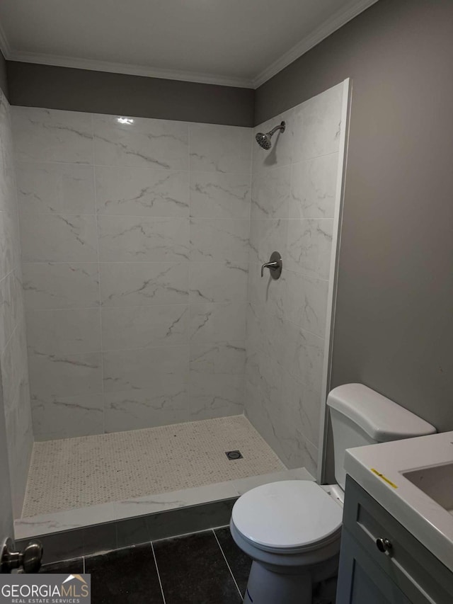 bathroom featuring vanity, a tile shower, ornamental molding, toilet, and tile patterned floors