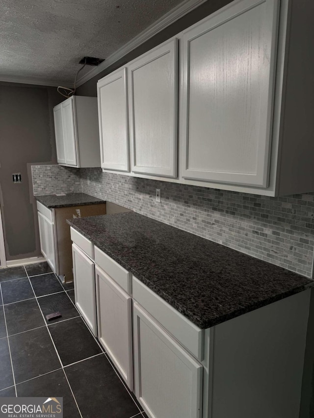 kitchen with dark stone counters, backsplash, dark tile patterned flooring, and white cabinets